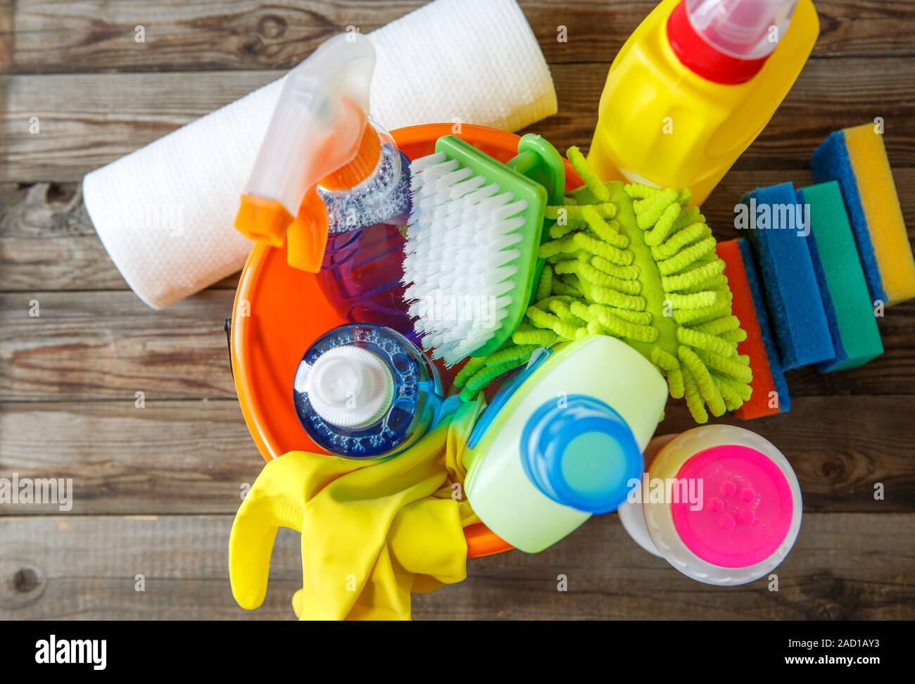 Secchio di plastica con materiali per la pulizia su uno sfondo di legno Foto Stock