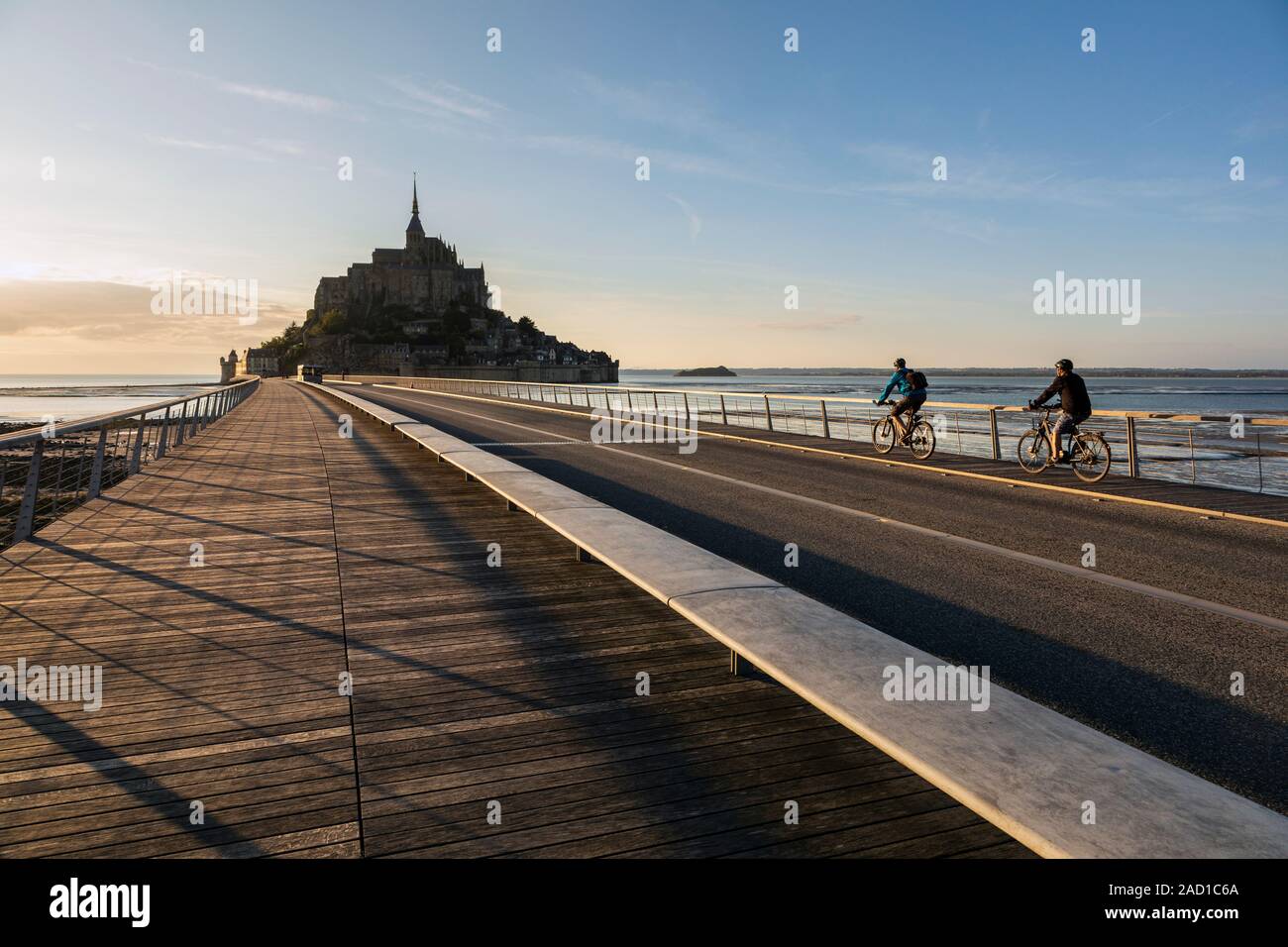 I ciclisti attraversando il ponte al Mont Saint Michel, in Normandia, Francia Foto Stock