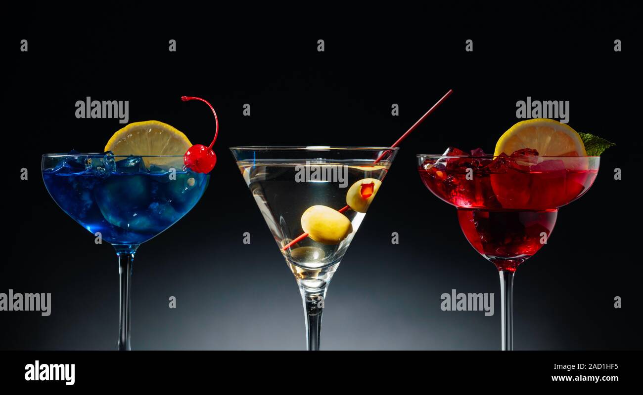 Due cocktail colorati e martini dry con olive verdi. Il rosso e il blu  cocktail con ghiaccio, limone, menta e ciliegia Foto stock - Alamy