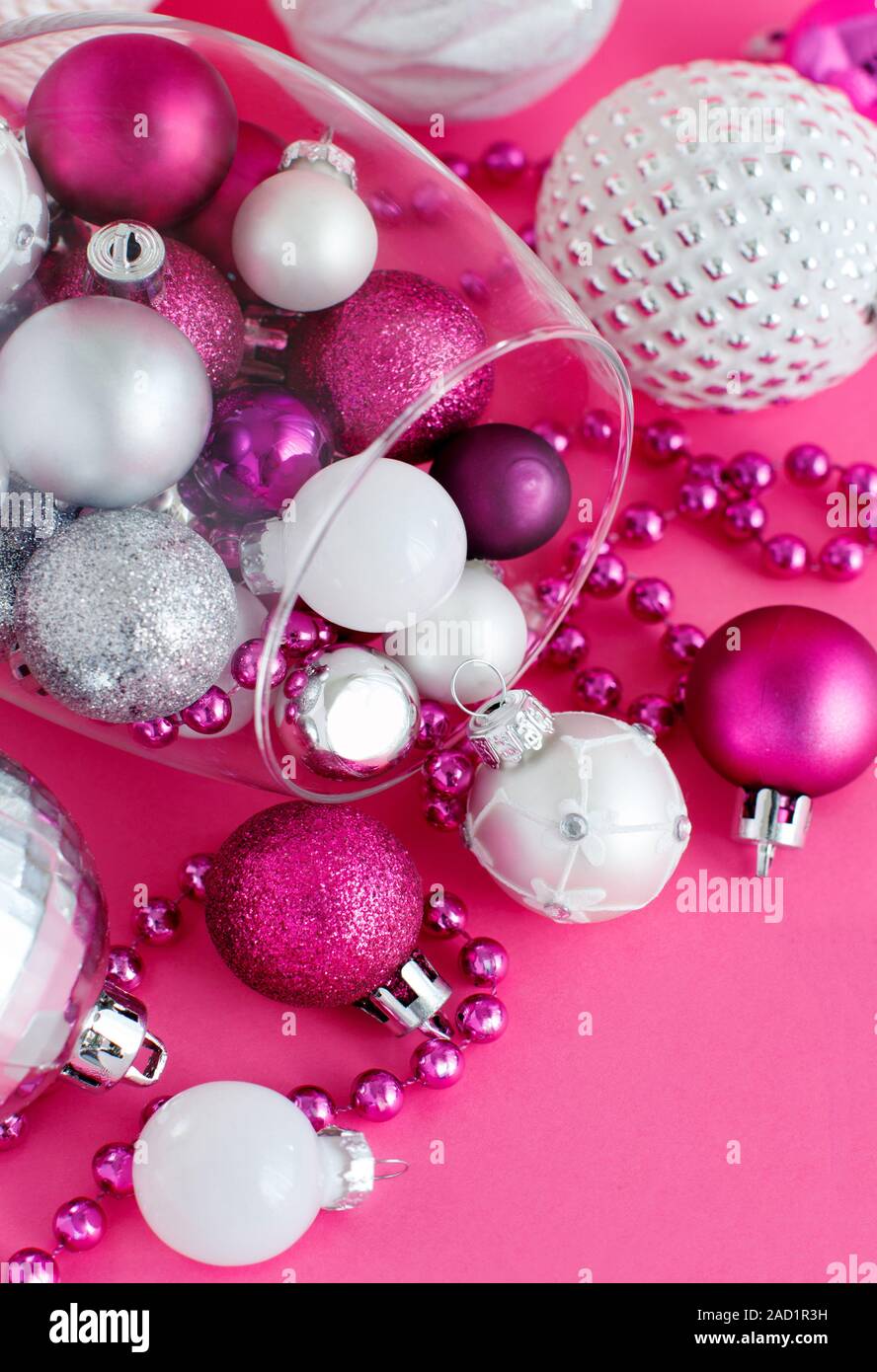 Baubles di natale in un bicchiere di vino su uno sfondo rosa close up Foto Stock