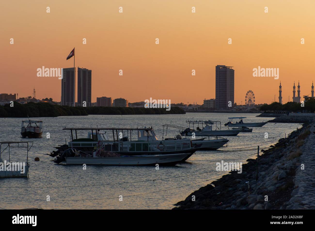 Panorama di un Ras al Khaimah vista della bandiera pole e moschea come il sole tramonta in flusso di giallo e arancione. Foto Stock