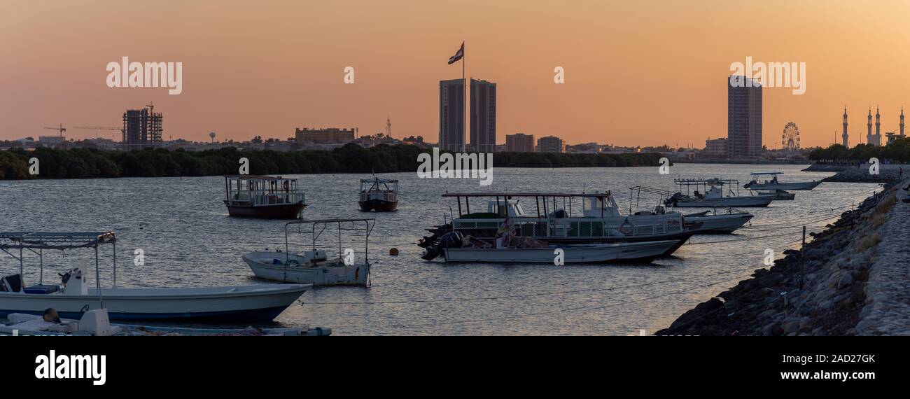 Panorama di un Ras al Khaimah vista della bandiera pole e moschea come il sole tramonta in flusso di giallo e arancione. Foto Stock