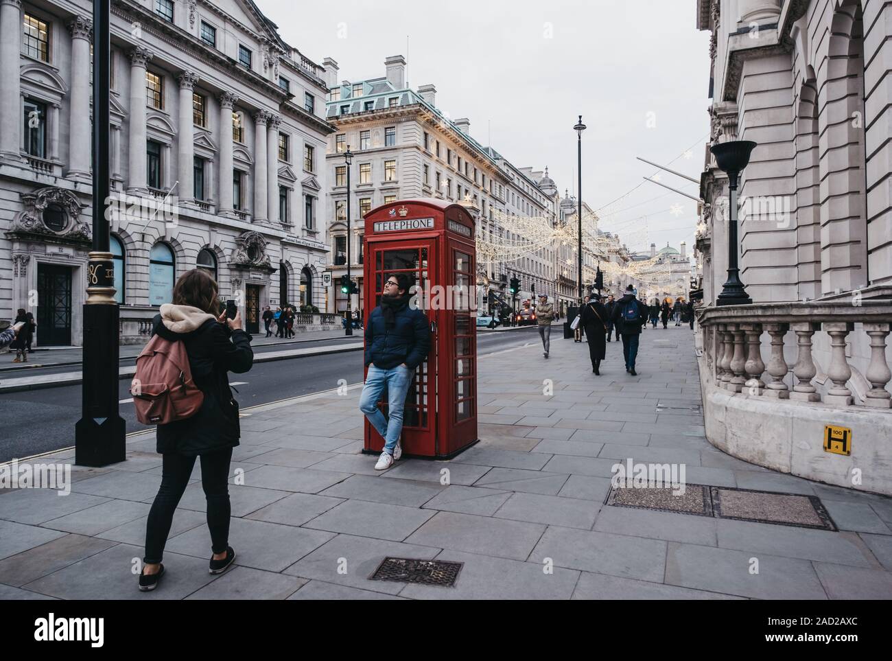 London, Regno Unito - Novembre 24,2019: turisti scattare foto dal telefono rosso stand in Regent Street di San Giacomo, un punto di riferimento 200-year-old street nella città di Westm Foto Stock