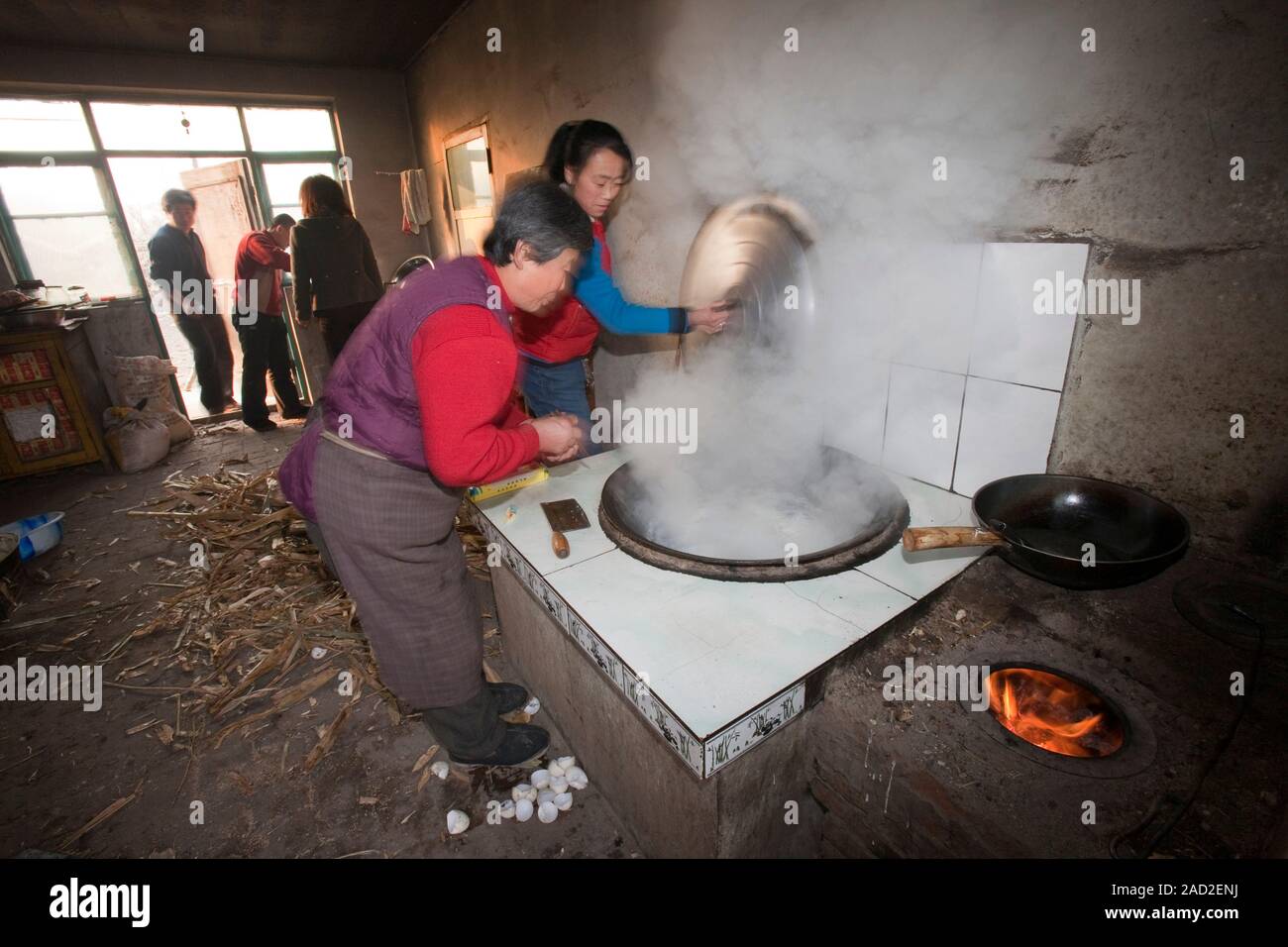 Una famiglia cinese cuochi su una stufa alimentata da essiccato stocchi  mais e pule che non solo cuoce il cibo e riscalda l'acqua ma anche riscalda  la casa. P Foto stock -