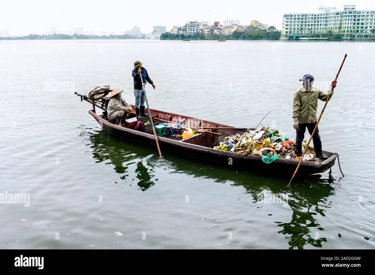Due uomini sulla barca eliminazione rifiuti da Red River Hanoi Vietnam Foto Stock