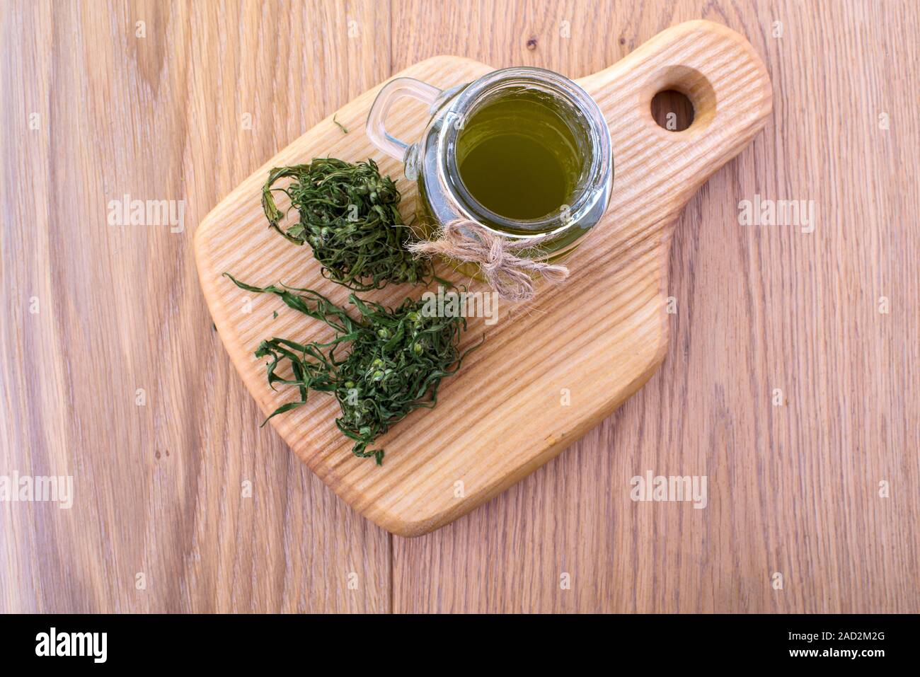 Olio di canapa in un vasetto di vetro, foglie di cannabis sullo sfondo delle tavole di legno. Vista dall'alto. Foto Stock