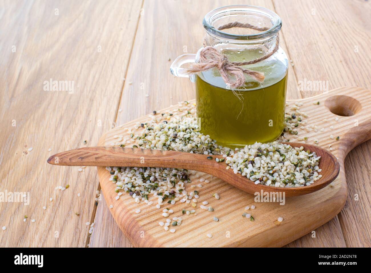 Olio di canapa in un vasetto di vetro e di sementi di canapa in un cucchiaio sulla superficie in legno Foto Stock