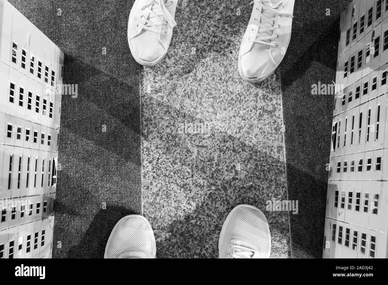 Vista dall'alto di due paia di scarpe da ginnastica, gambe di amare giovane Foto Stock