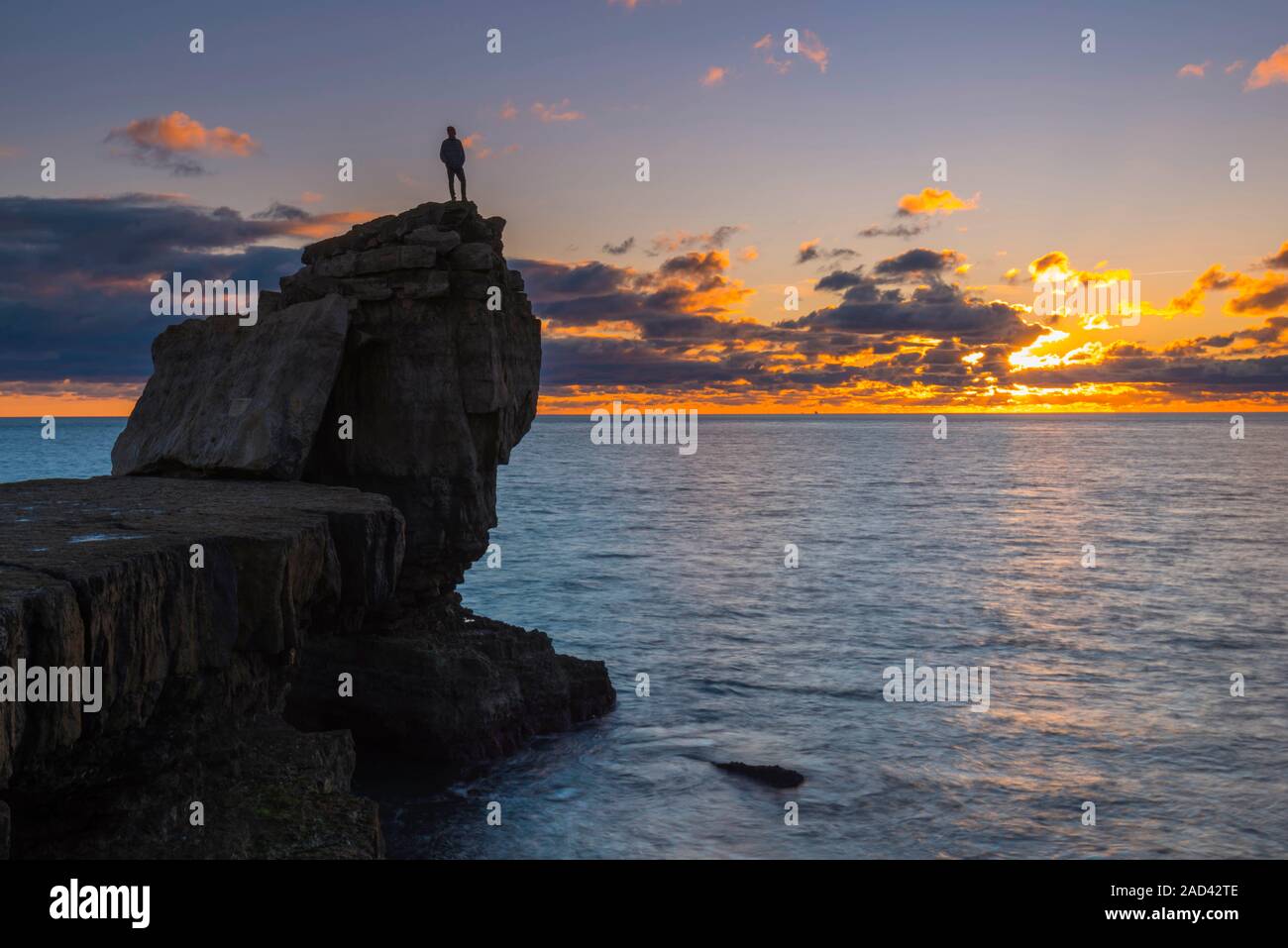 Portland Bill, Dorset, Regno Unito. Il 3° dicembre 2019. Regno Unito Meteo. Un uomo sorge sulla sommità del pulpito Rock al Portland Bill in Dorset per visualizzare il tramonto spettacolare alla fine di un freddo soleggiato inverni giorno. Credito Foto: Graham Hunt/Alamy Live News Foto Stock