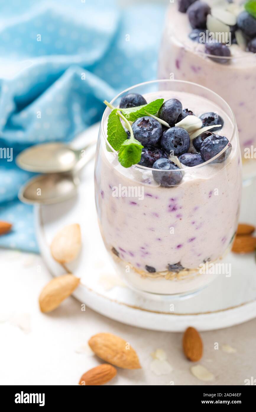 Lo yogurt greco o di mirtillo parfait con frutti di bosco freschi e mandorla dadi su sfondo bianco, mangiare sano Foto Stock