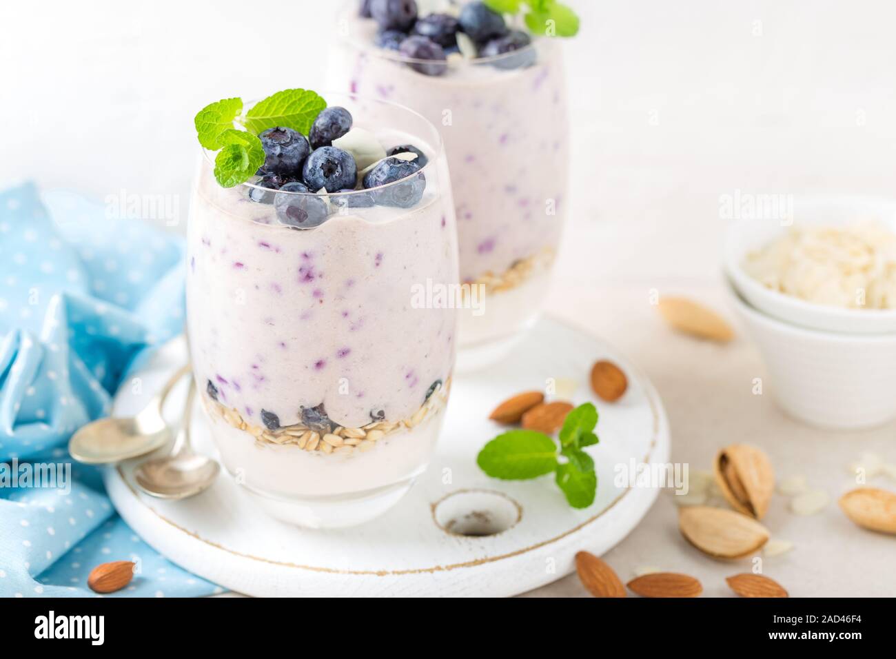 Lo yogurt greco o di mirtillo parfait con frutti di bosco freschi e mandorla dadi su sfondo bianco, mangiare sano Foto Stock