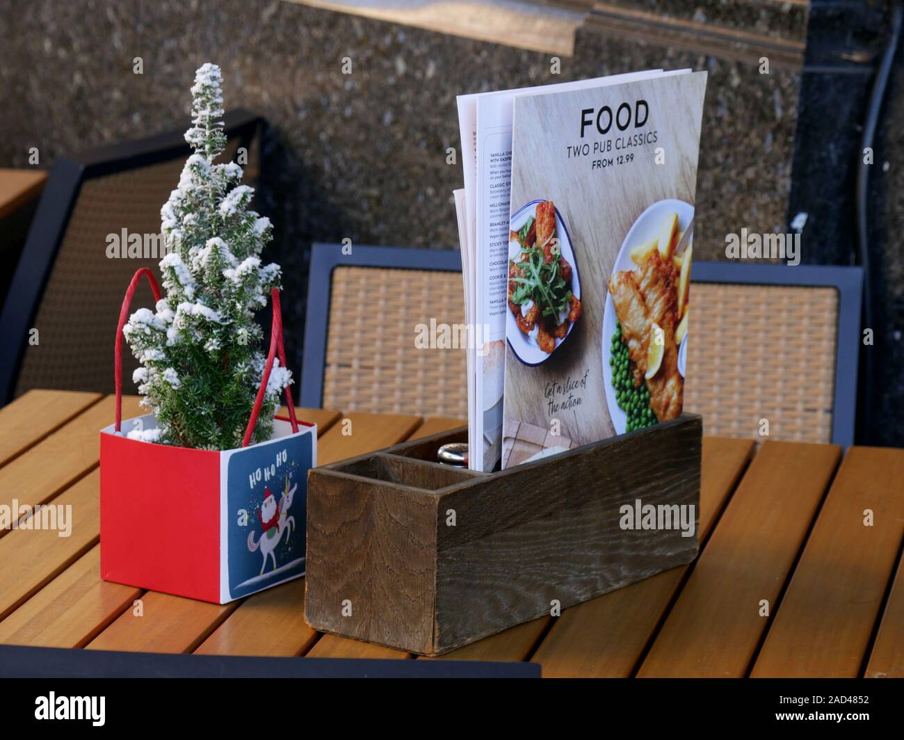 Piccolo albero di Natale in un sacchetto e menu sul tavolo al di fuori di un pub locale Foto Stock