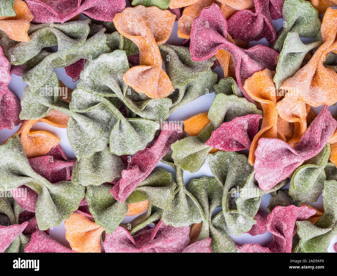 Pila di essiccato italiano Tricolore farfalle di pasta, sfondo vari colori del filtro bow tie Foto Stock
