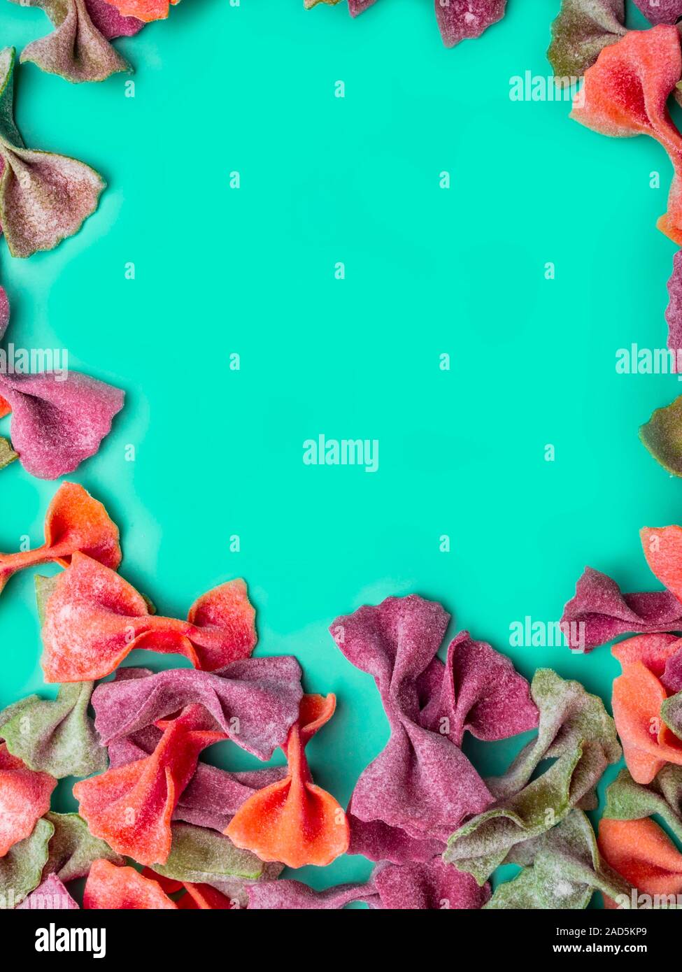 Pila di essiccato italiano Tricolore farfalle di pasta. Vari colori di bow tie su moda verde menta colore di sfondo Foto Stock