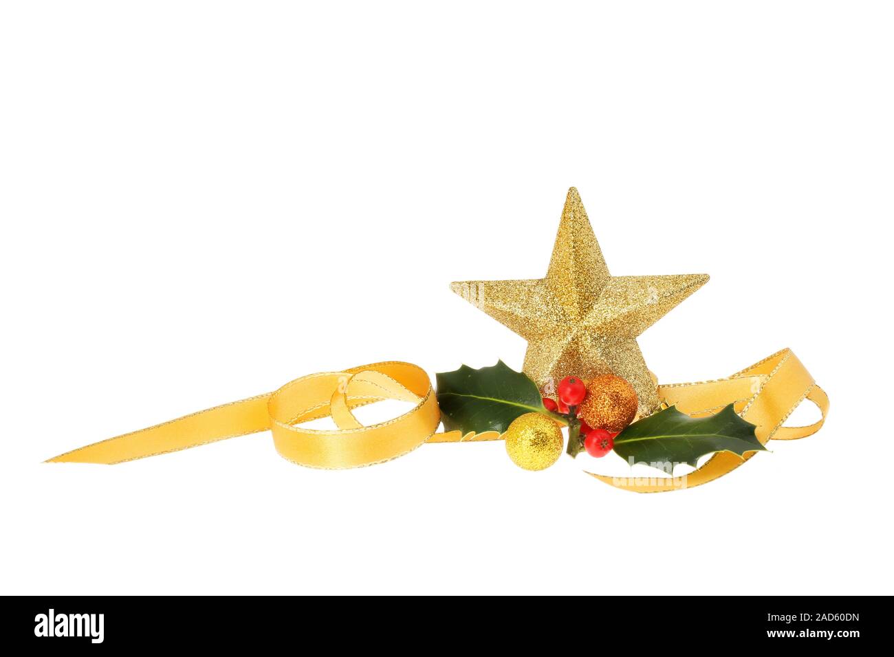 Decorazione di natale, oro glitter star e baubles con agrifoglio e una spirale di nastro oro isolata contro bianco Foto Stock