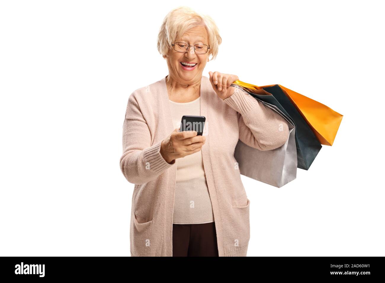 Donna anziana il trasporto delle borse della spesa e guardando un telefono cellulare isolato su sfondo bianco Foto Stock