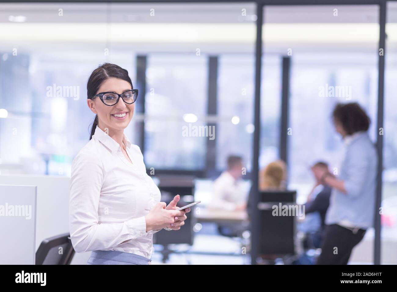 Donna elegante tramite telefono cellulare in startup edificio per uffici Foto Stock