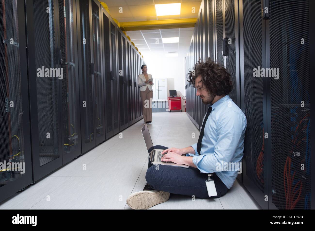 Team di giovani tecnici che lavorano insieme su server Foto Stock