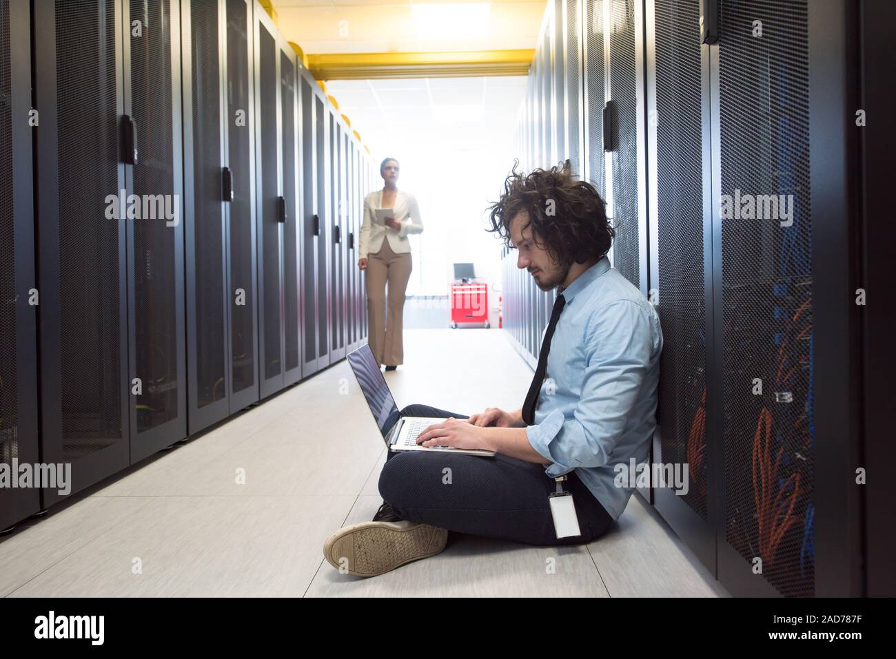 Team di giovani tecnici che lavorano insieme su server Foto Stock