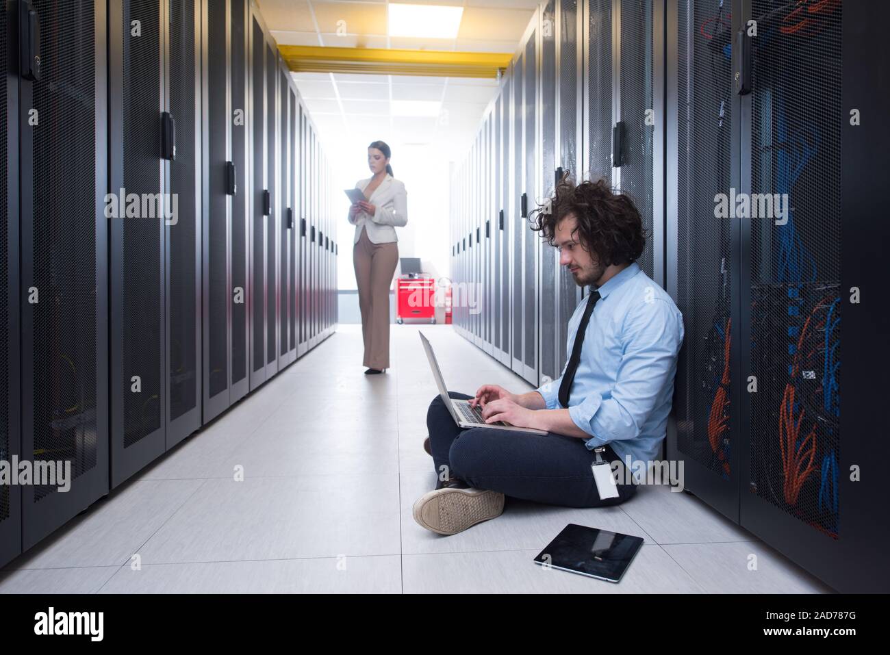 Team di giovani tecnici che lavorano insieme su server Foto Stock