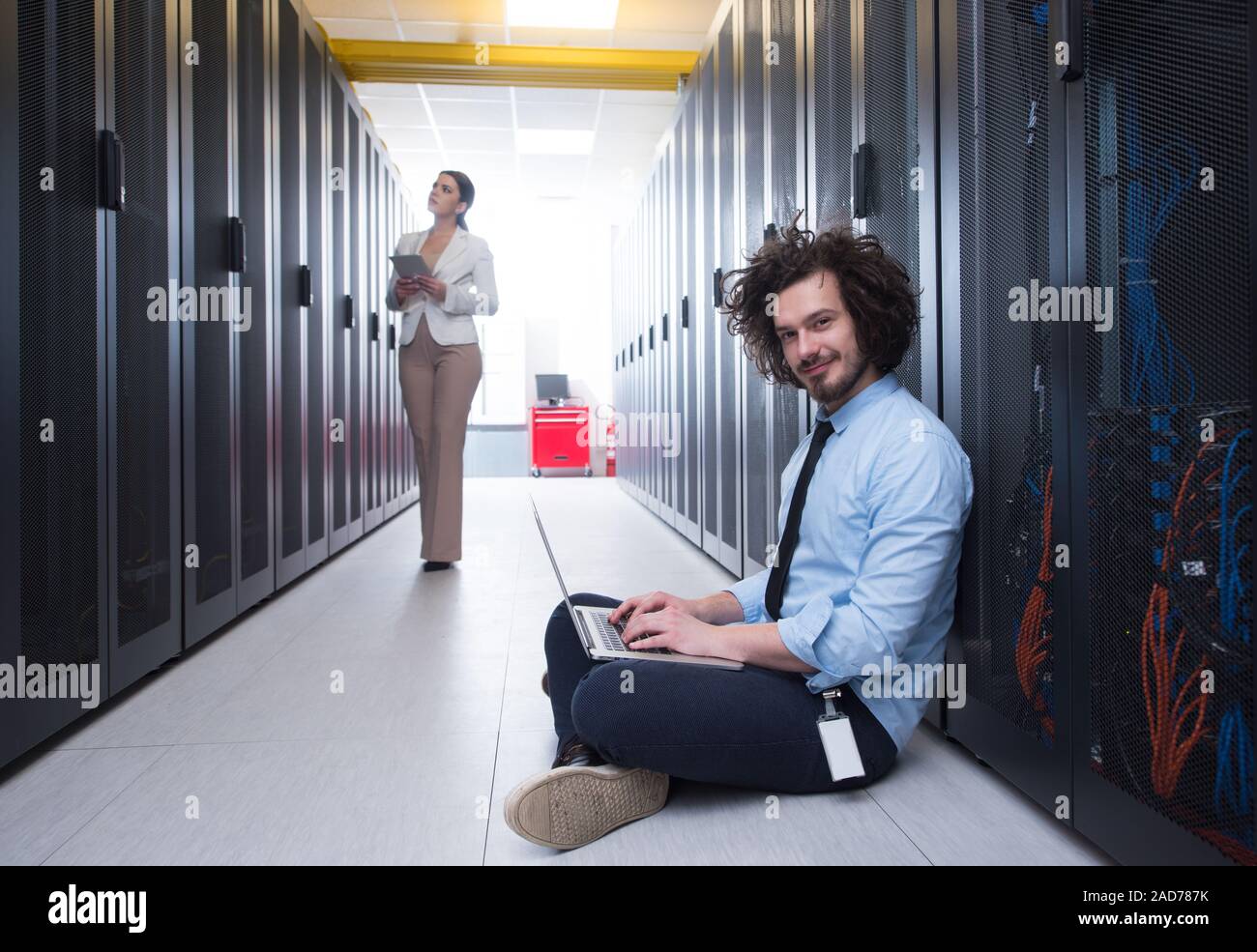 Team di giovani tecnici che lavorano insieme su server Foto Stock