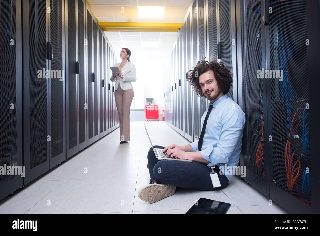 Team di giovani tecnici che lavorano insieme su server Foto Stock
