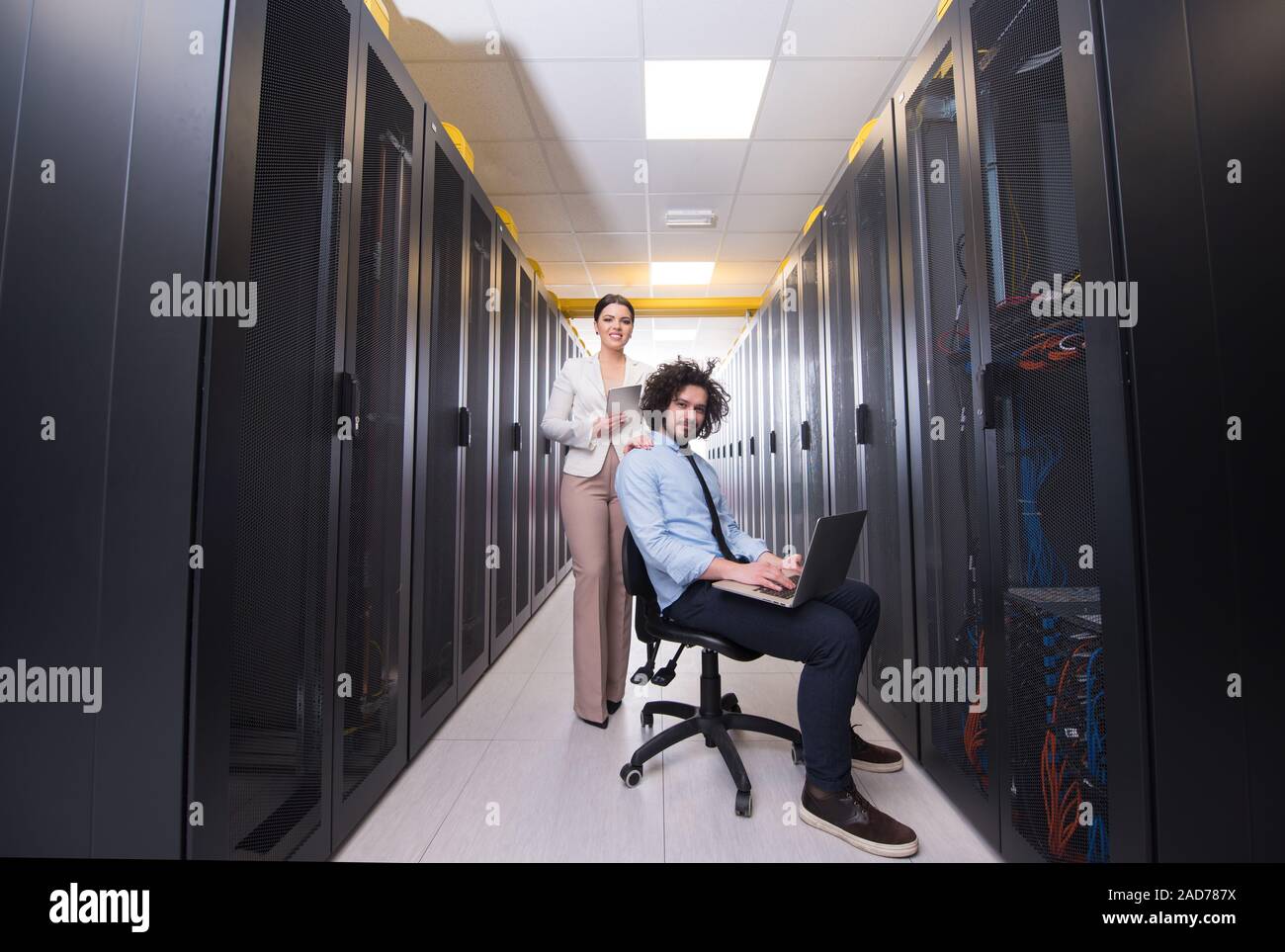 Team di giovani tecnici che lavorano insieme su server Foto Stock