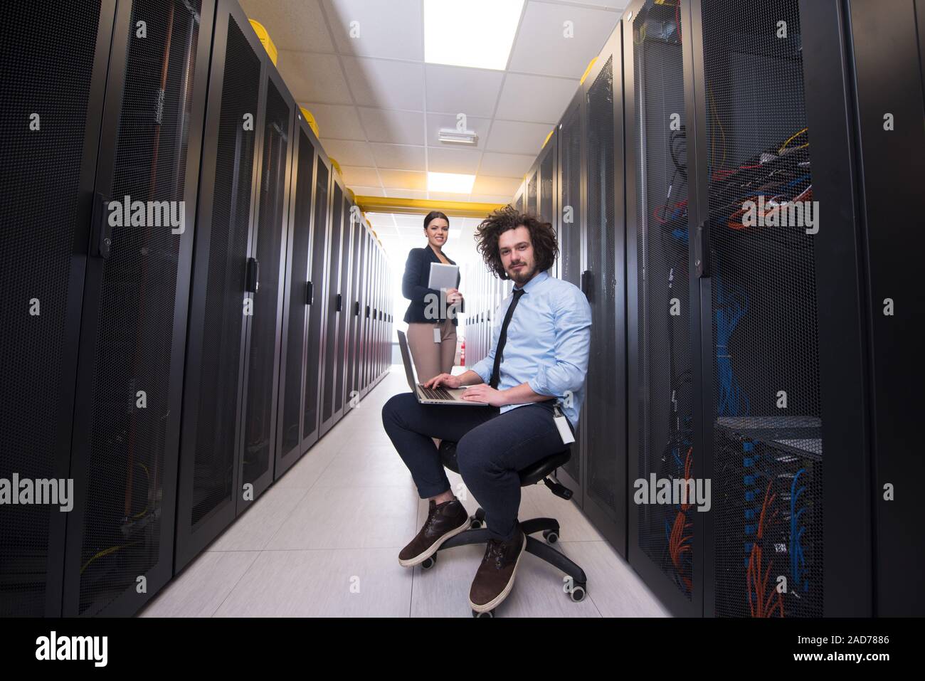 Team di giovani tecnici che lavorano insieme su server Foto Stock