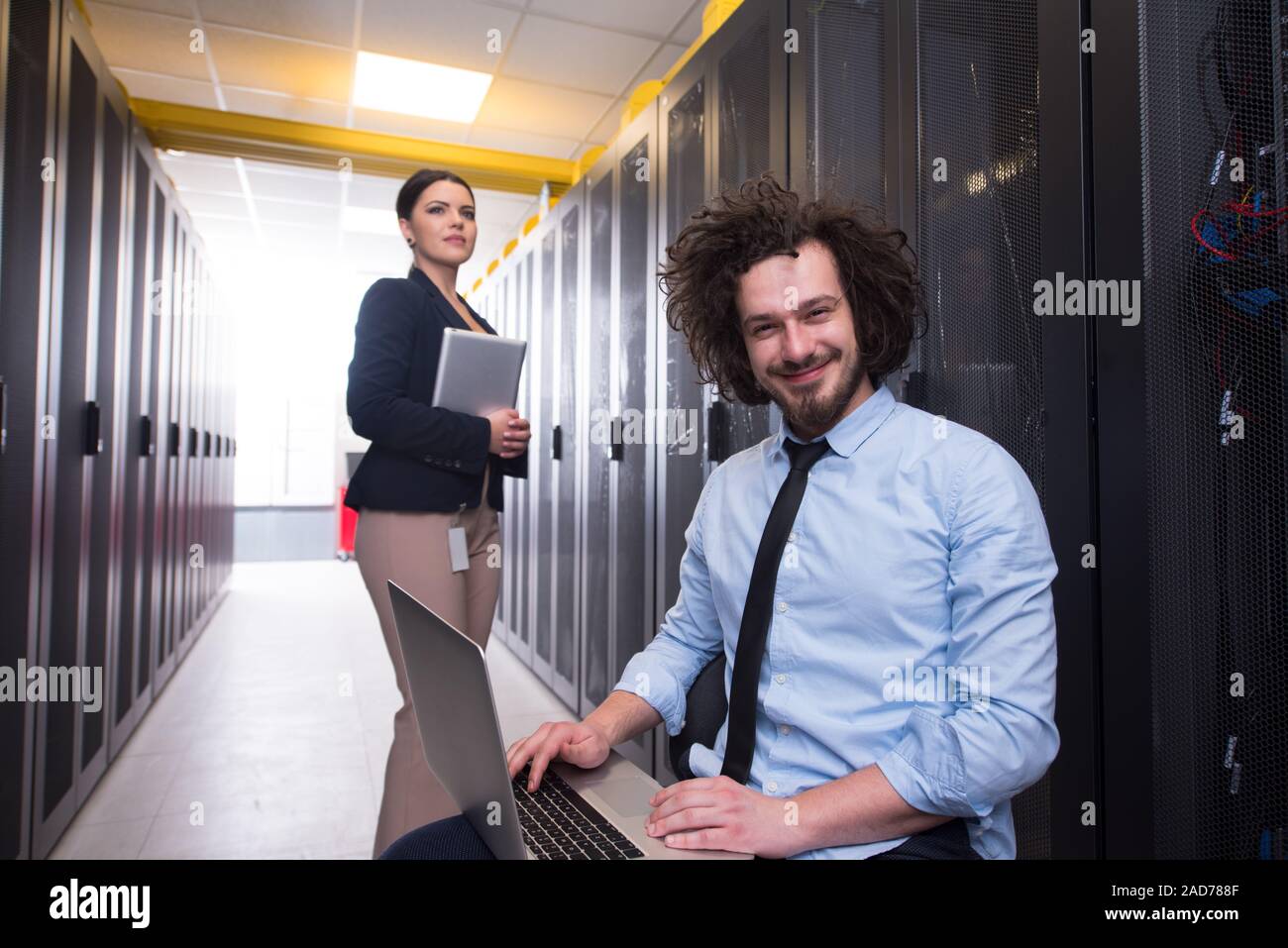 Team di giovani tecnici che lavorano insieme su server Foto Stock