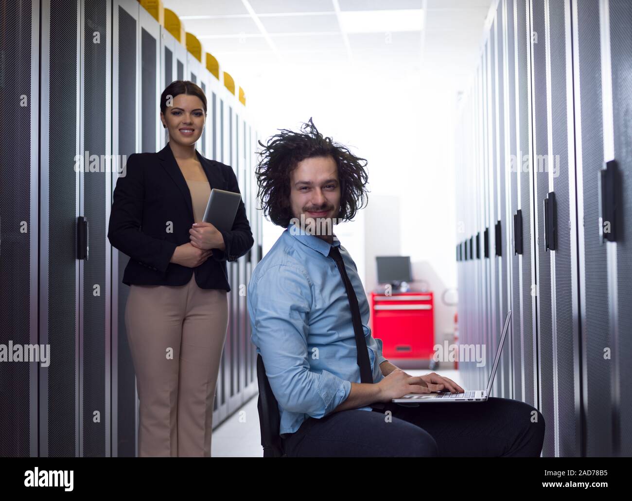 Team di giovani tecnici che lavorano insieme su server Foto Stock