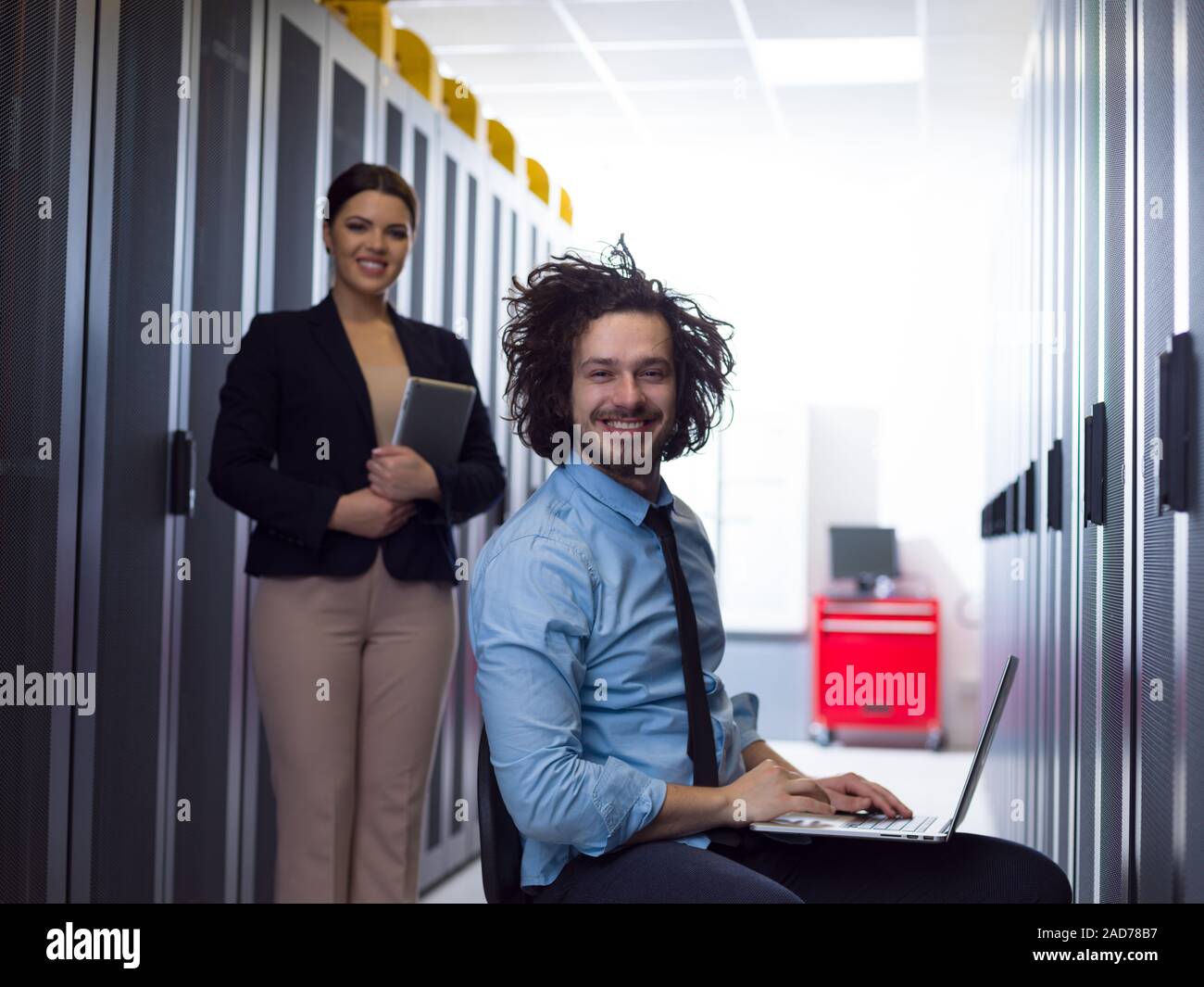 Team di giovani tecnici che lavorano insieme su server Foto Stock