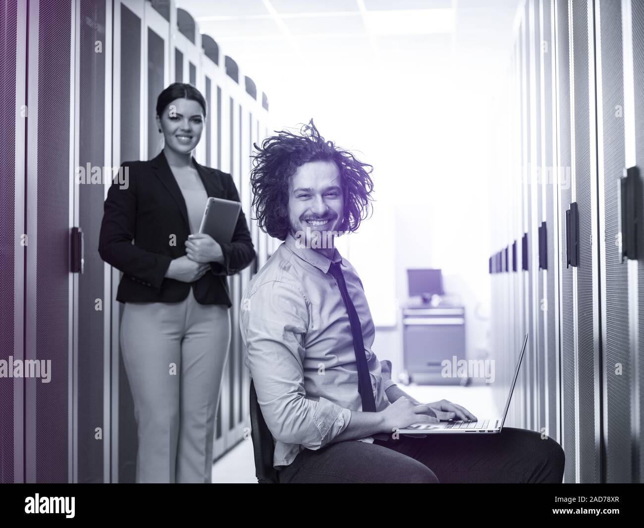 Team di giovani tecnici che lavorano insieme su server Foto Stock