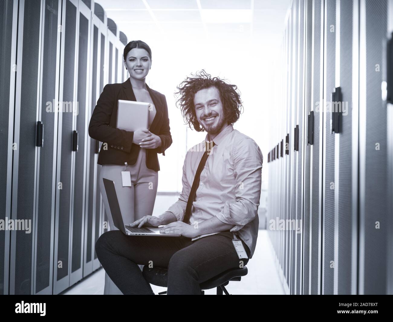 Team di giovani tecnici che lavorano insieme su server Foto Stock