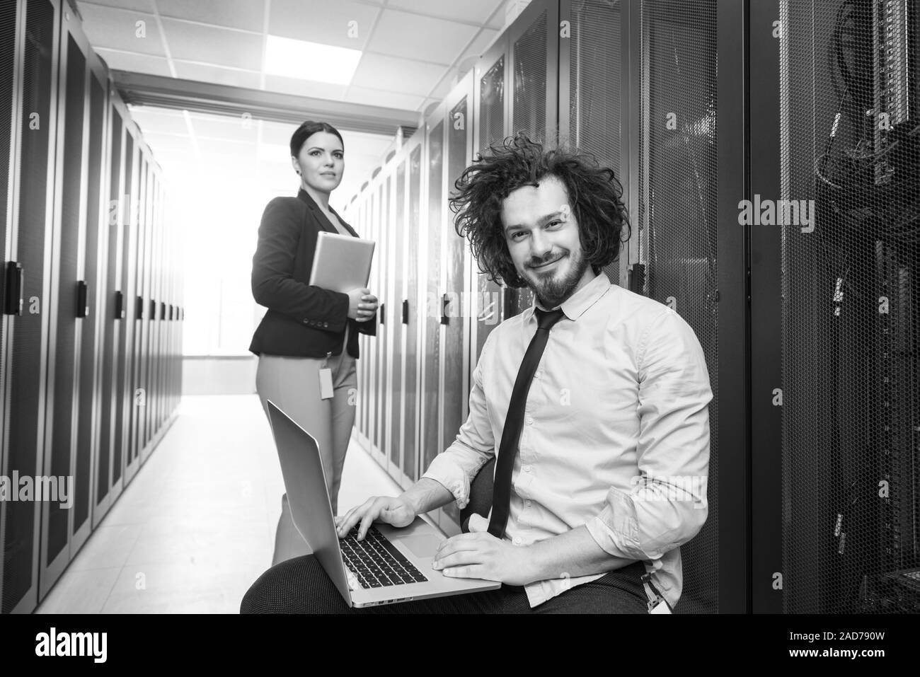 Team di giovani tecnici che lavorano insieme su server Foto Stock