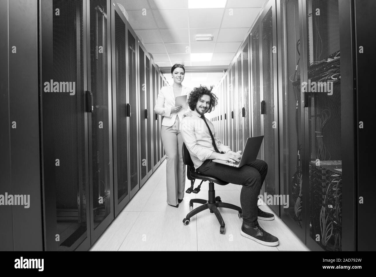 Team di giovani tecnici che lavorano insieme su server Foto Stock