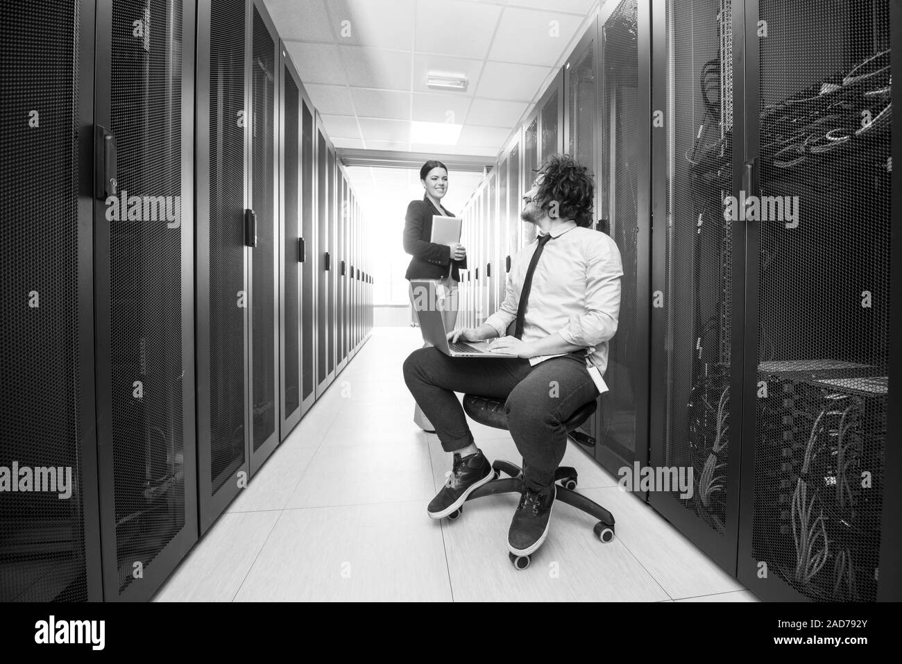 Team di giovani tecnici che lavorano insieme su server Foto Stock