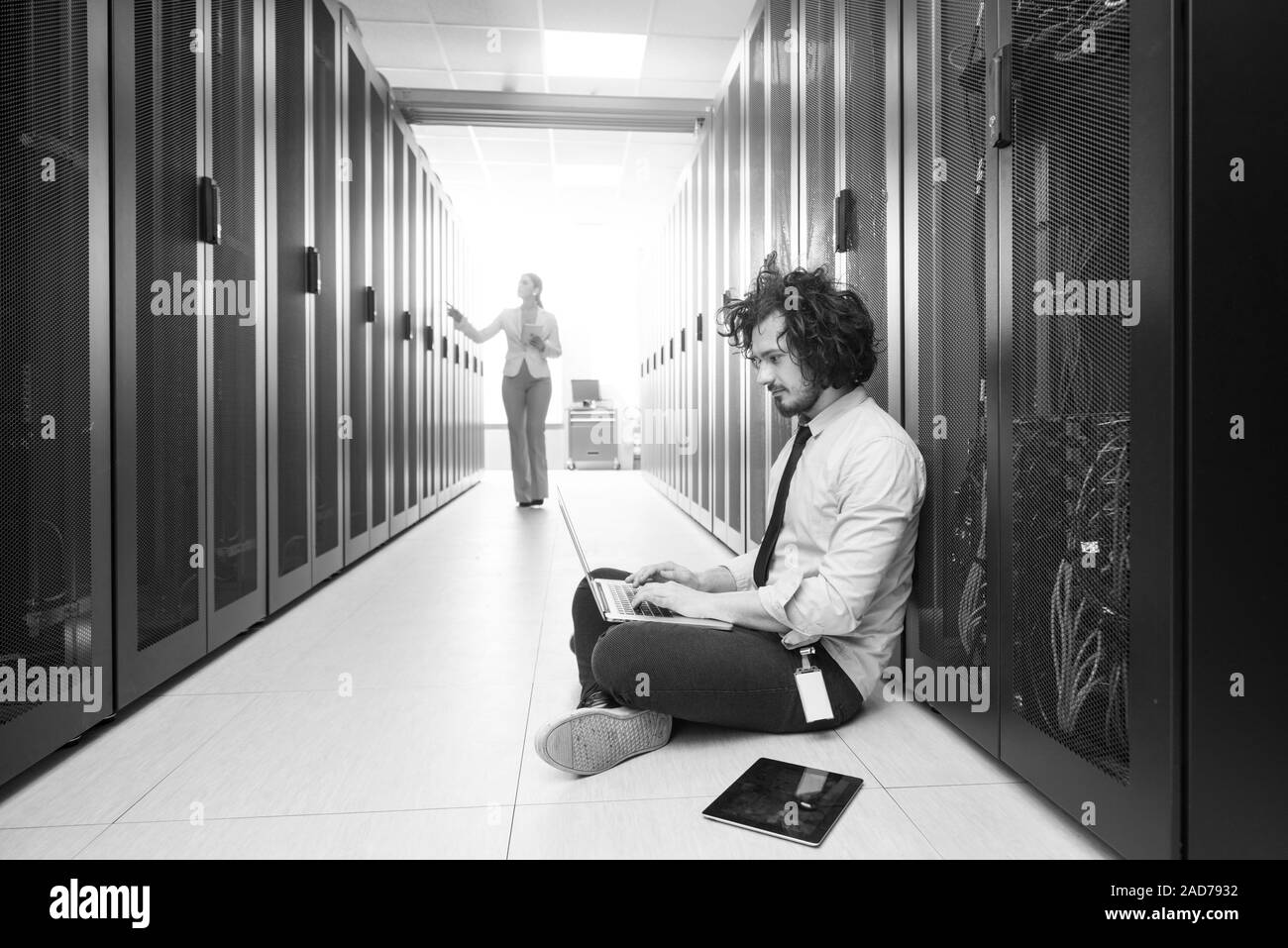 Team di giovani tecnici che lavorano insieme su server Foto Stock