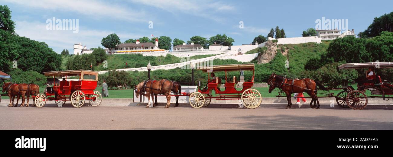 Stati Uniti d'America, Michigan, Contea di Mackinac, isola di Mackinac, carrelli a cavallo al di fuori di un edificio Foto Stock