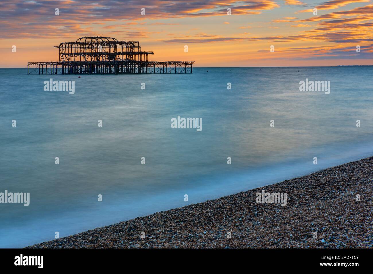 I resti del molo Ovest di Brighton visto al tramonto Foto Stock
