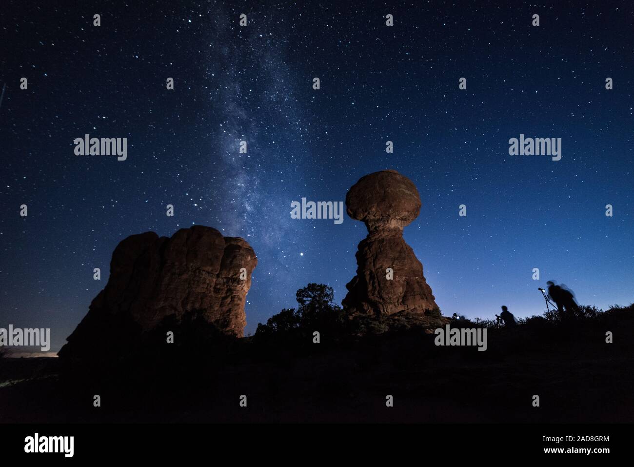 I fotografi al crepuscolo di scattare le foto alla Via Lattea dietro la roccia equilibrato, Arches National Park, STATI UNITI D'AMERICA Foto Stock