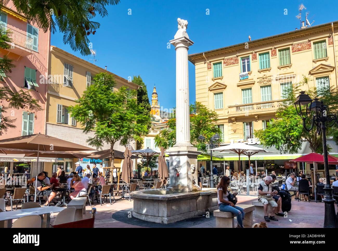 La gente del posto e i turisti godetevi un pomeriggio di sole in una piccola piazza nel centro della città vecchia sezione di Menton, Francia, sulla Riviera Francese. Foto Stock