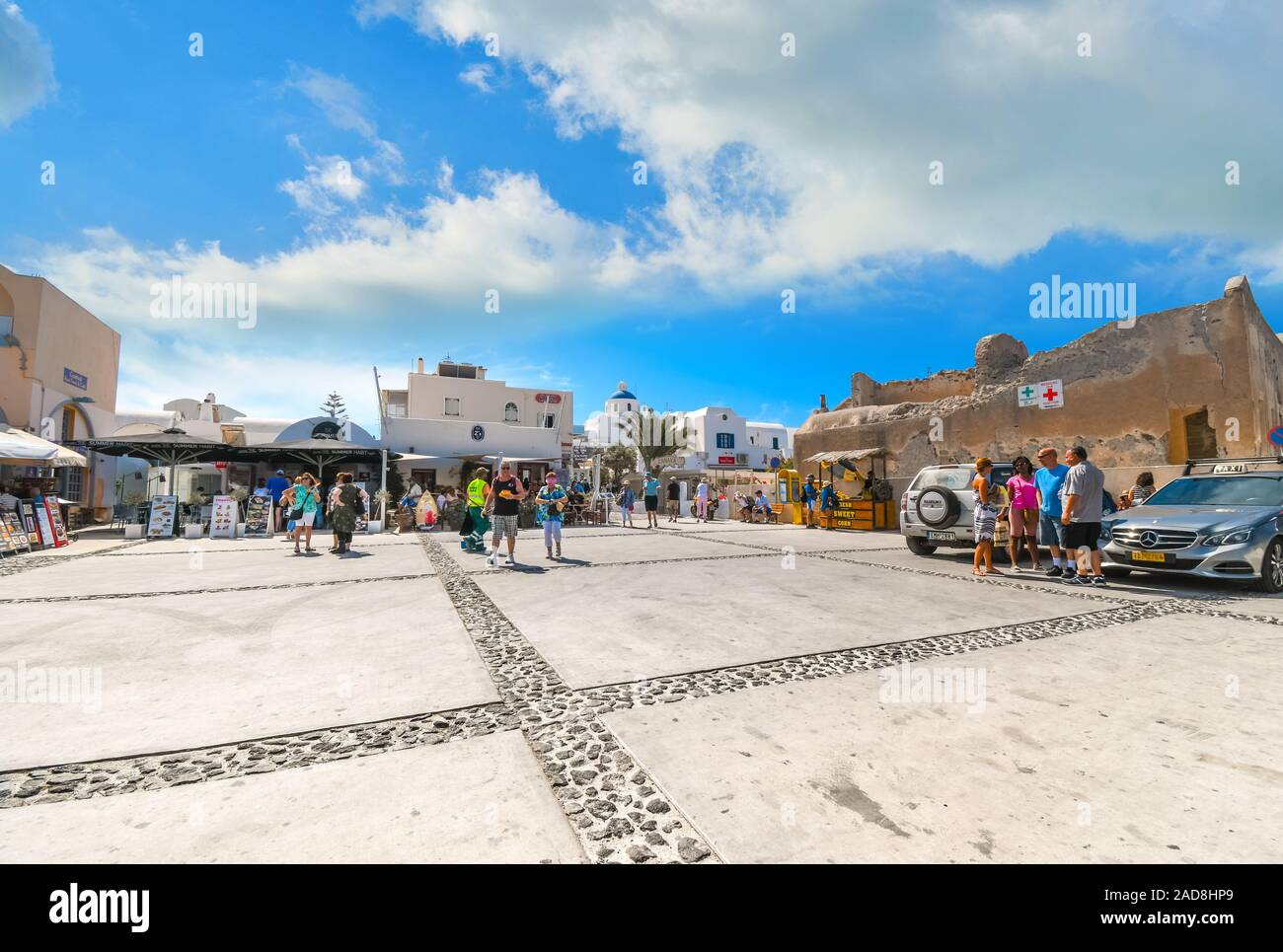I turisti passeggiare sulla piazza di fronte alla chiesa di Panagia come loro di entrare nel villaggio di Oia a Santorini, Grecia. Foto Stock
