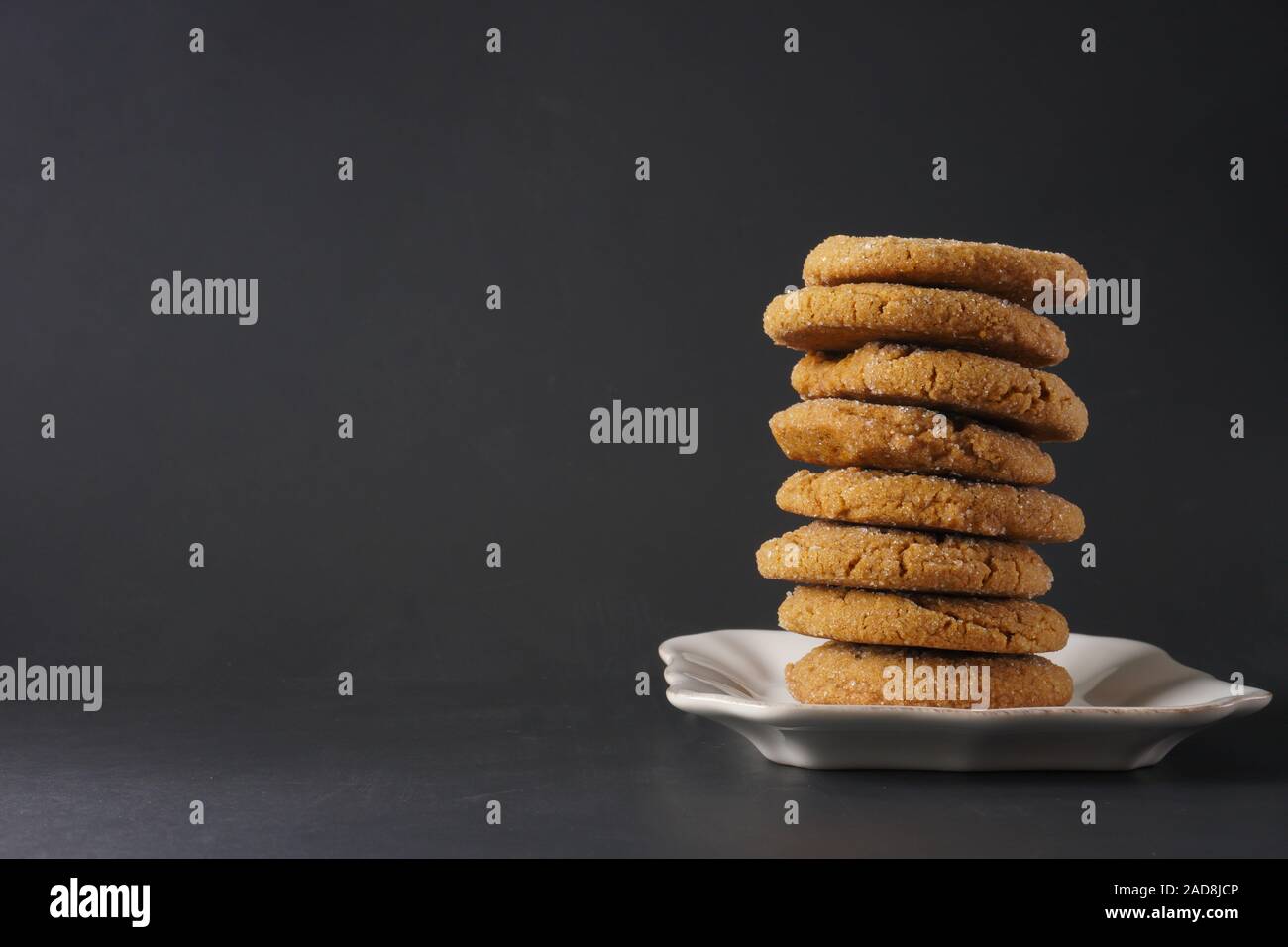 Una pila di gingerbread cookie su una piastra bianca con uno sfondo nero; spazio di copia Foto Stock