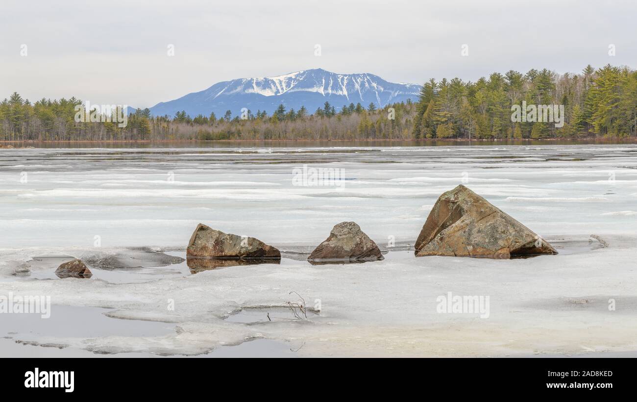 Katahdin dietro un Congelato stagno con rocce frastagliate in primo piano. Foto Stock
