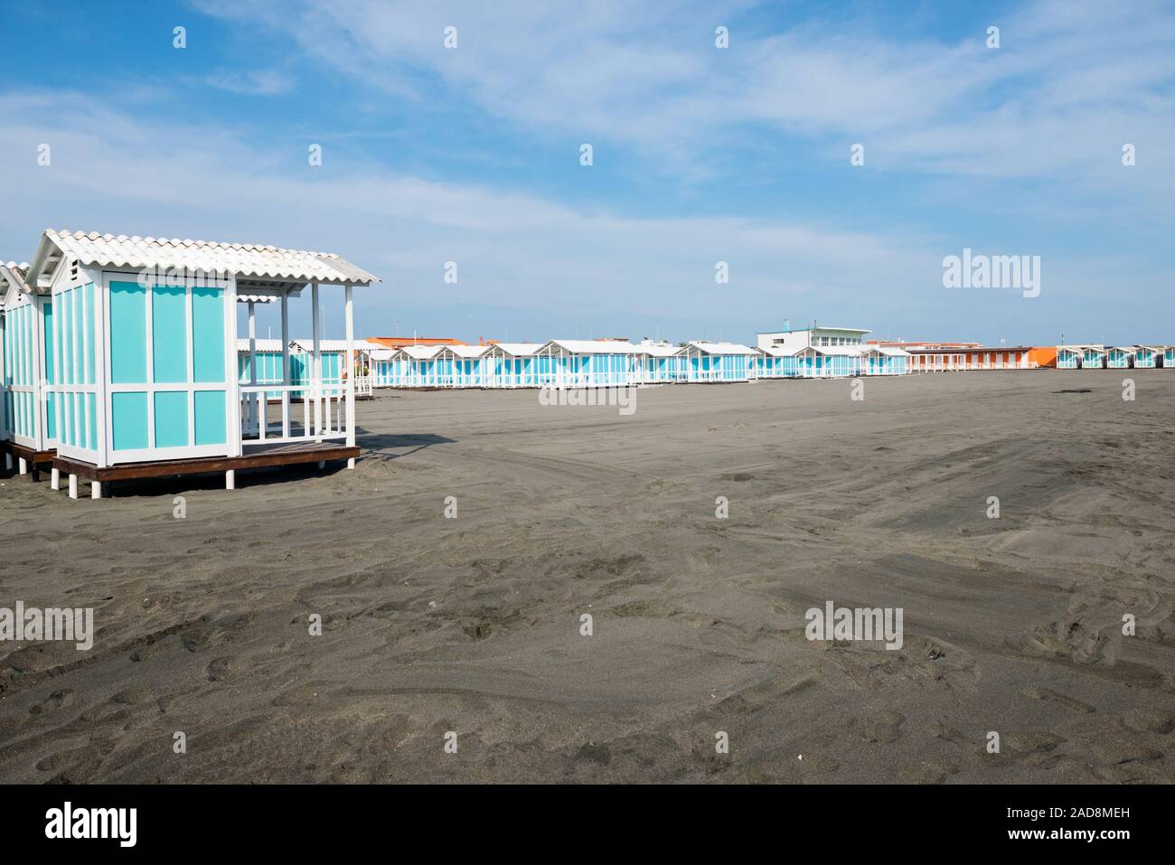 Bella spiaggia di sabbia nera e bianca e a strisce blu case sulla spiaggia, mare Tirreno vicino a Roma, Italia Foto Stock