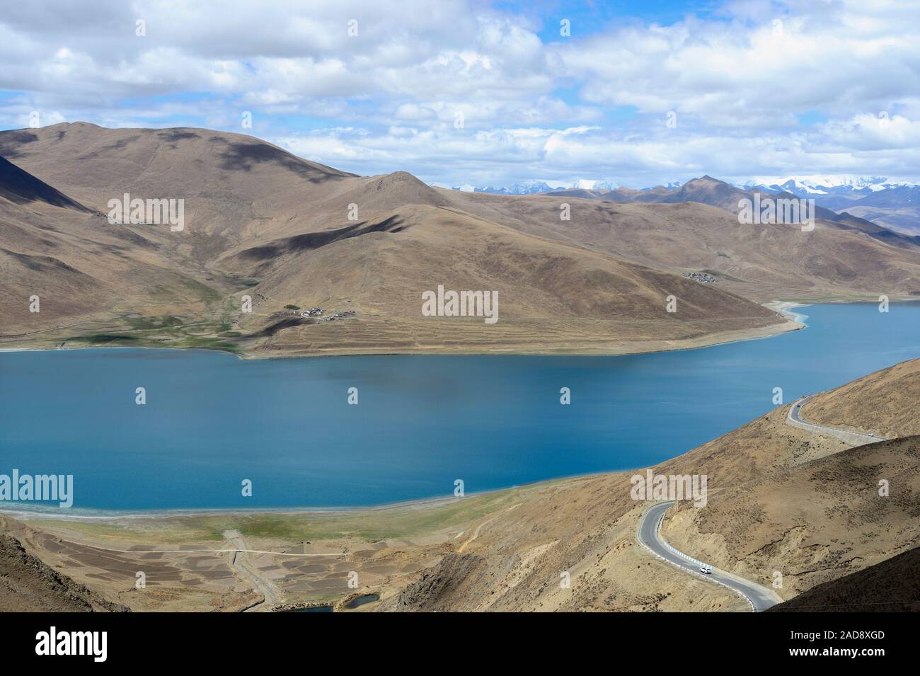 Al di sotto di una pletora di puffy, il bianco delle nuvole, Lago Yamdrok si illumina di color turchese nel Brahmaputra Valley della regione autonoma del Tibet della Cina. Foto Stock