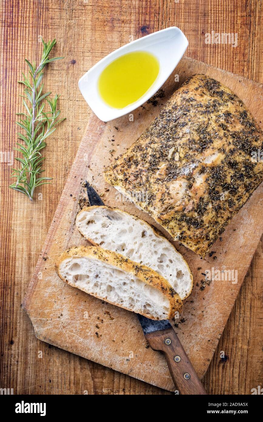 Italiano tradizionale pane ciabatta con erbe e olio di oliva come vista dall'alto su un tagliere Foto Stock