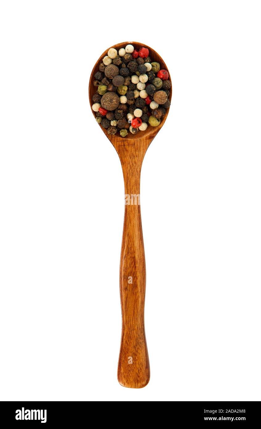 Una miscela di peperoni in un cucchiaio di legno su isolare. Vista da sopra. La stagionatura in un cucchiaio. Spice sul isolare. Foto Stock