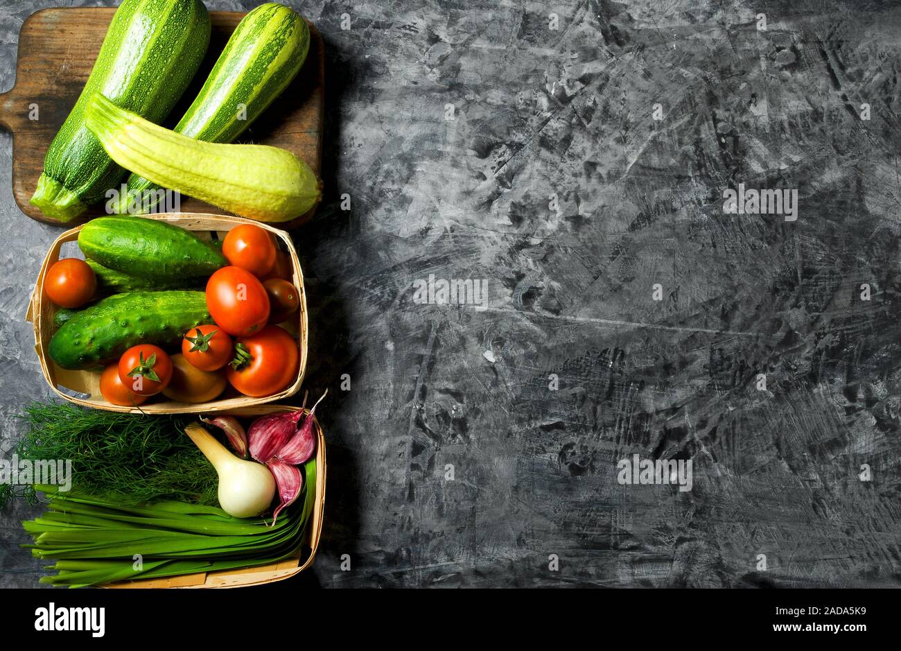 Verdure sullo sfondo. Ortaggi freschi (cetrioli, pomodori, cipolle, aglio, aneto, fagioli verdi) su sfondo grigio. A Foto Stock