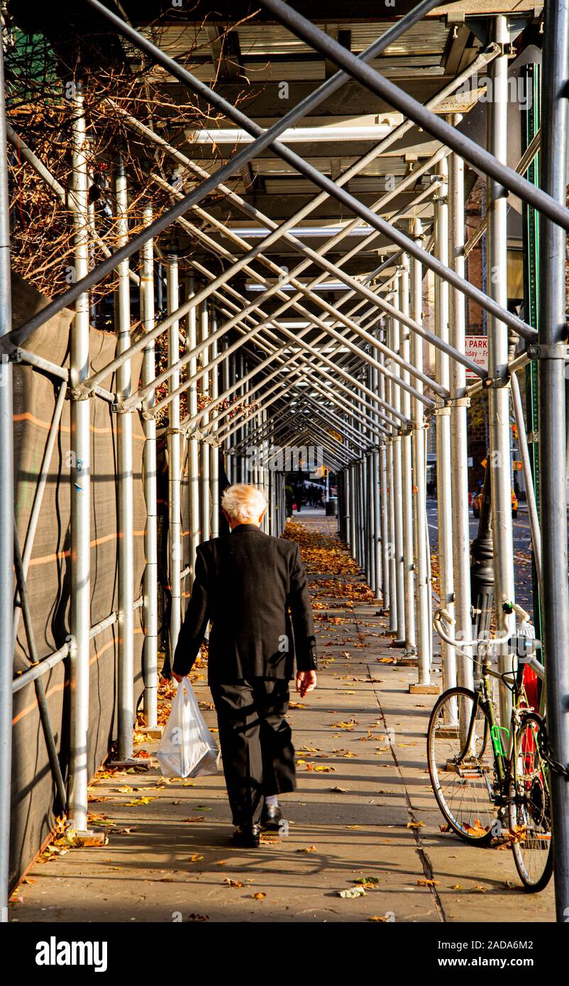 Vecchio che cammina in un tunnel di impalcatura Foto Stock